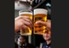 Two glasses full of beer held next to each other in a toast.