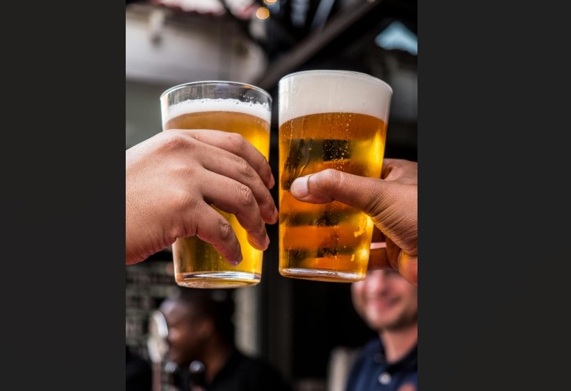 Two glasses full of beer held next to each other in a toast.