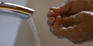 Male washing hands under faucet.