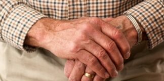 Older man leans on walking stick.
