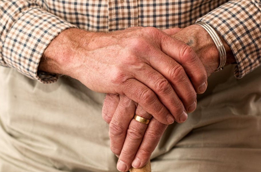 Older man leans on walking stick.