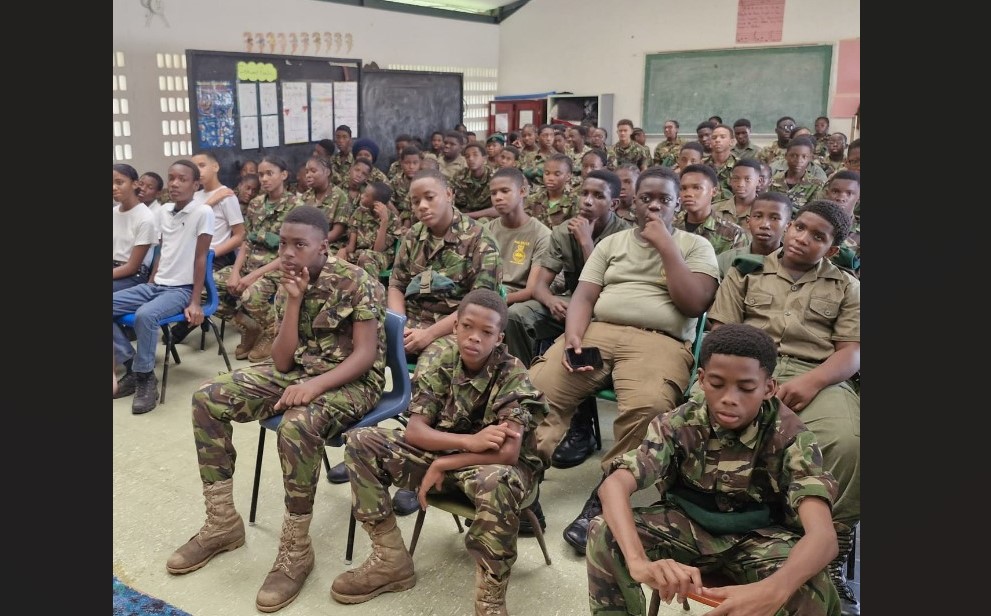 Young members of the Saint Lucia Cadet Corps sit listening to a police lecture.