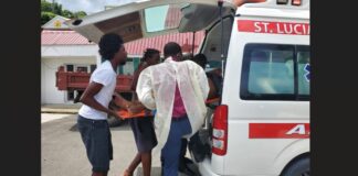 Emergency responder and public spirited citizens lift an injured scooter rider on a stretcher into an ambulance after he sustained injuries in a collision with a car.