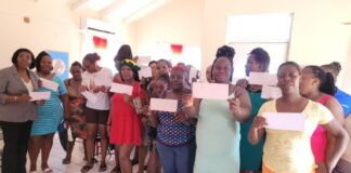 Emma Hippolyte poses with parents who received monetary support for their children who are returning to school.