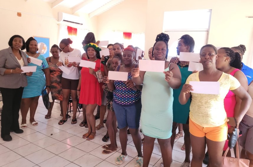 Emma Hippolyte poses with parents who received monetary support for their children who are returning to school.