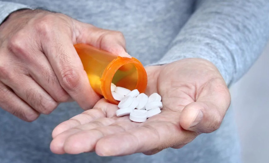 Man shaking tablets from a medicine bottle into one hand.