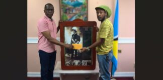 Prime Minister Philip J. Pierre presents envelope to Aaron Alexander.