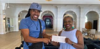 Rise Saint Lucia Inc. Chairman Dr. Venus Cherry accepts monetary donation from founder of Robinson Smiles foundation.