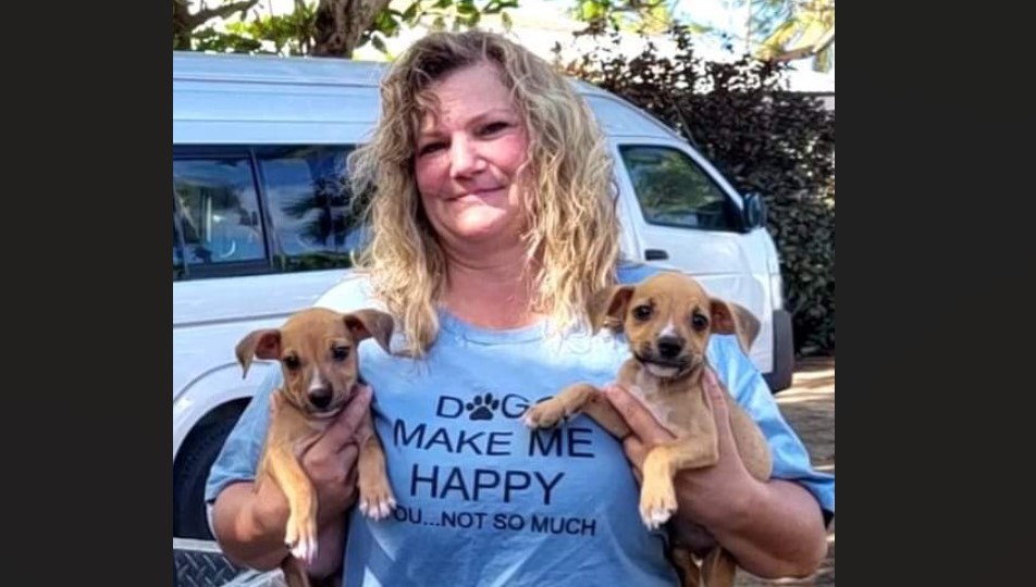 Woman holds two puppies.