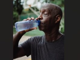 Sweating man drinks water from a bottle.