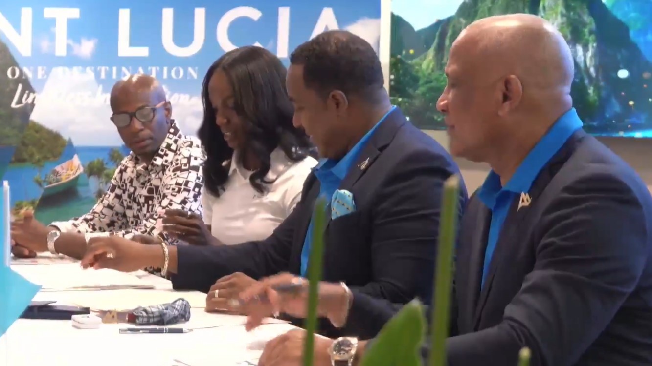 Julien Alfred signs document formally accepting role as Saint Lucia's Tourism Ambassador.